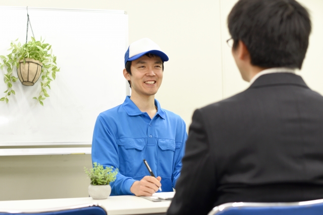 青い服の配達員と話すビジネスマン