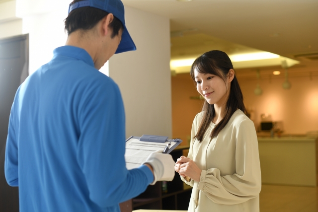 配達員から荷物を受け取る女性